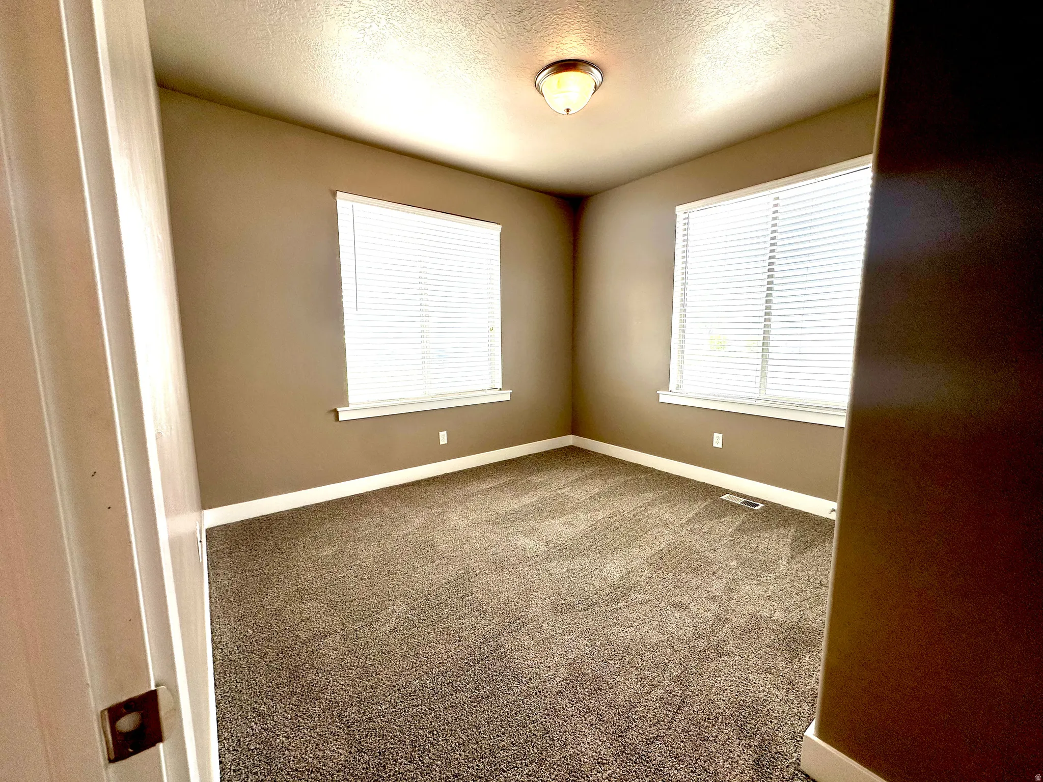 Carpeted spare room with baseboards and a textured ceiling