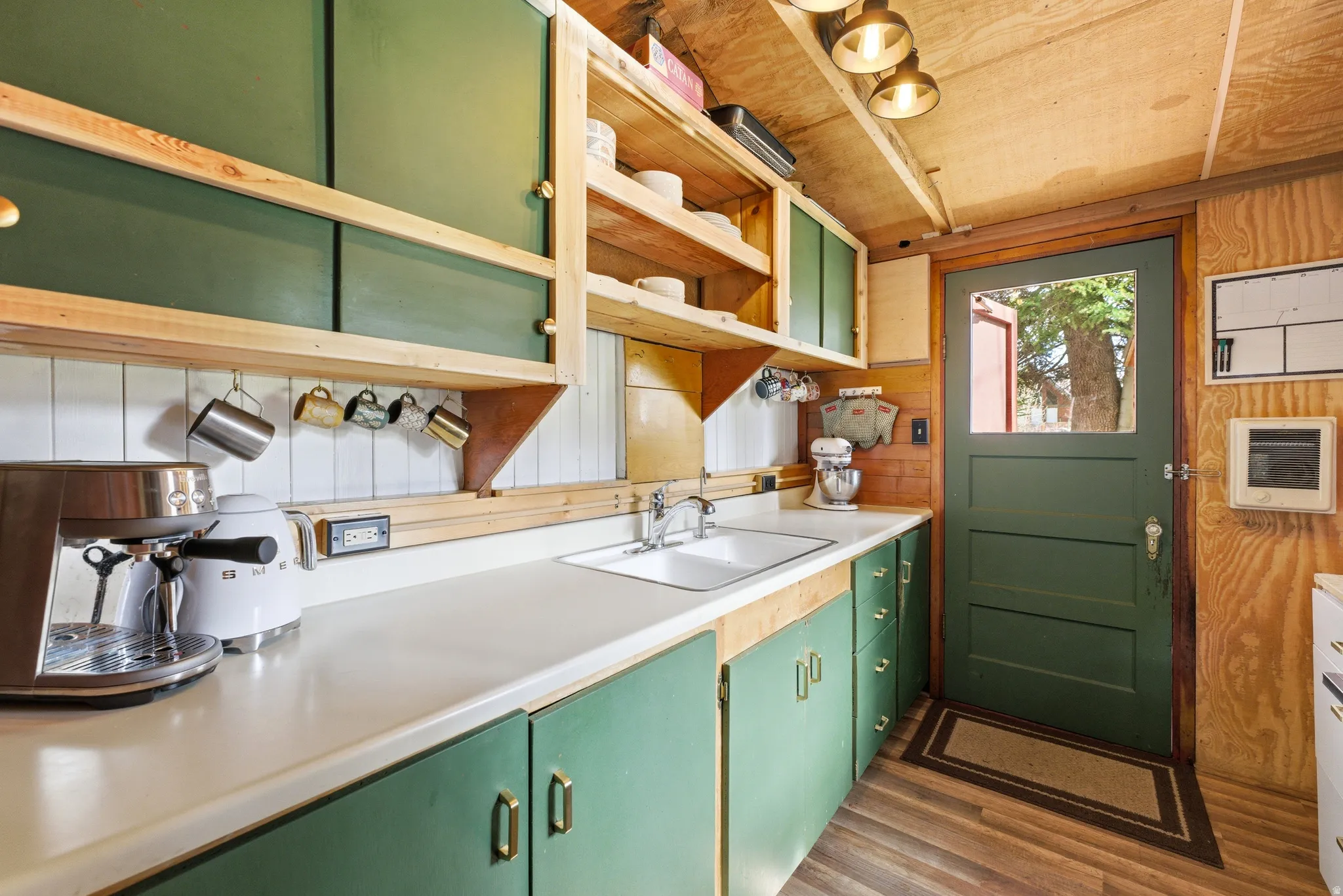 Kitchen featuring green cabinetry, light countertops, open shelves, wooden walls, and wooden ceiling