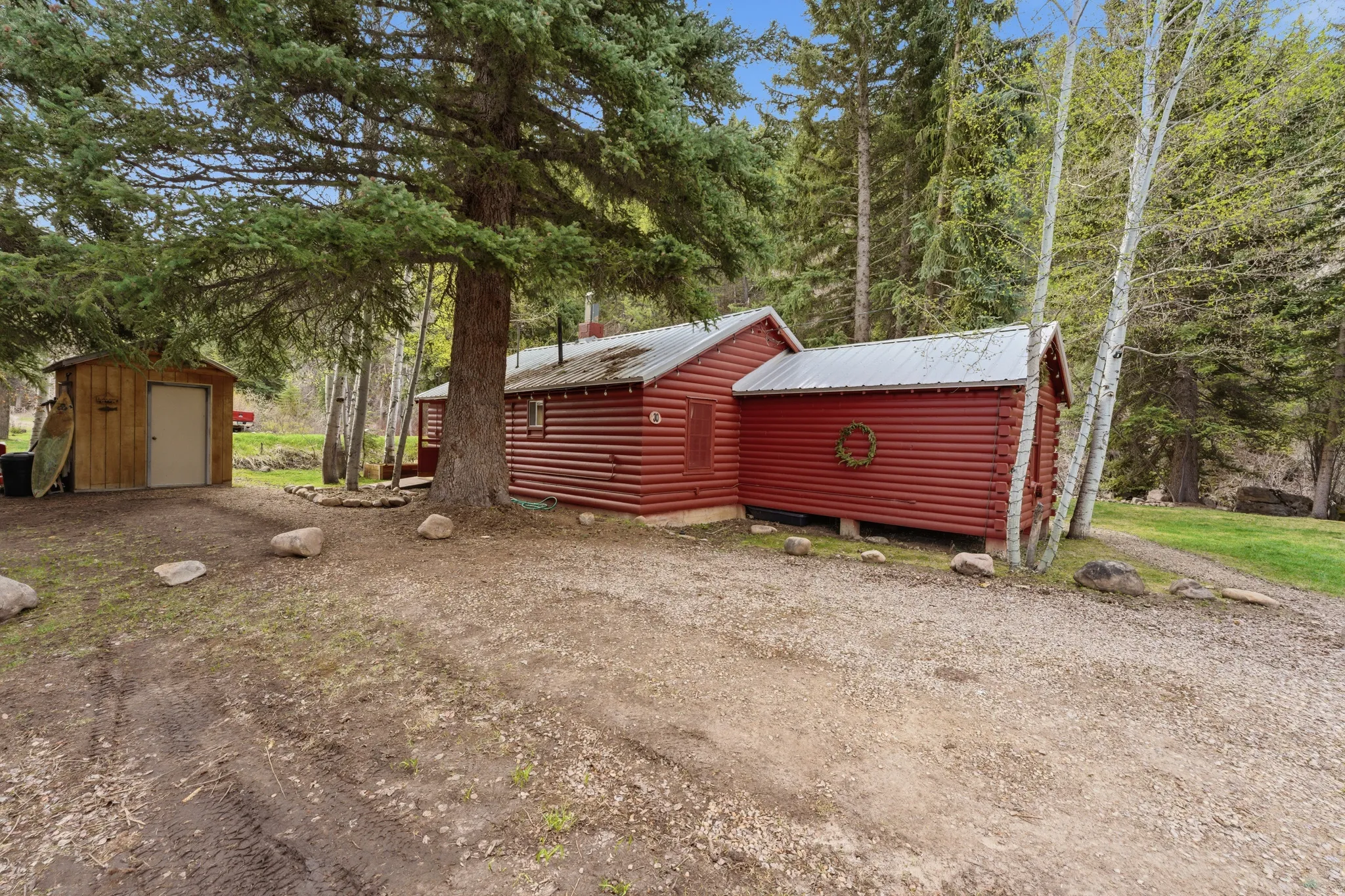View of property exterior with a storage unit, a metal roof, and log veneer siding