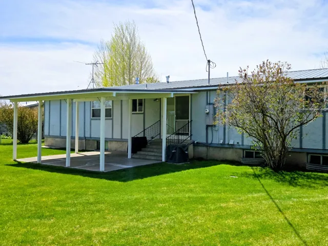 Back of house featuring a metal roof, a yard, a patio area, and board and batten siding