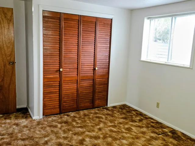 Unfurnished bedroom with a closet and dark colored carpet