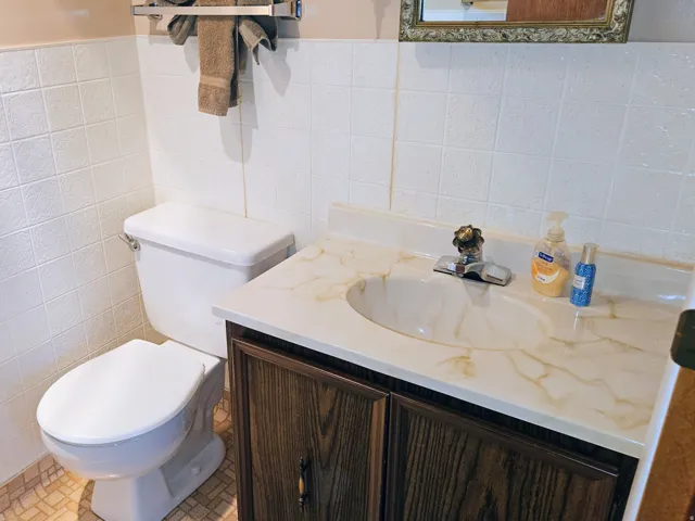 Half bath with vanity, tile walls, and a wainscoted wall