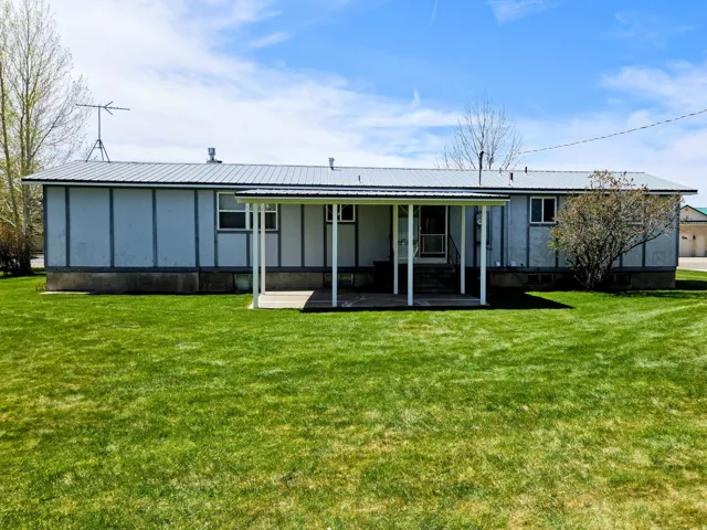 Back of property with a lawn, board and batten siding, and a metal roof