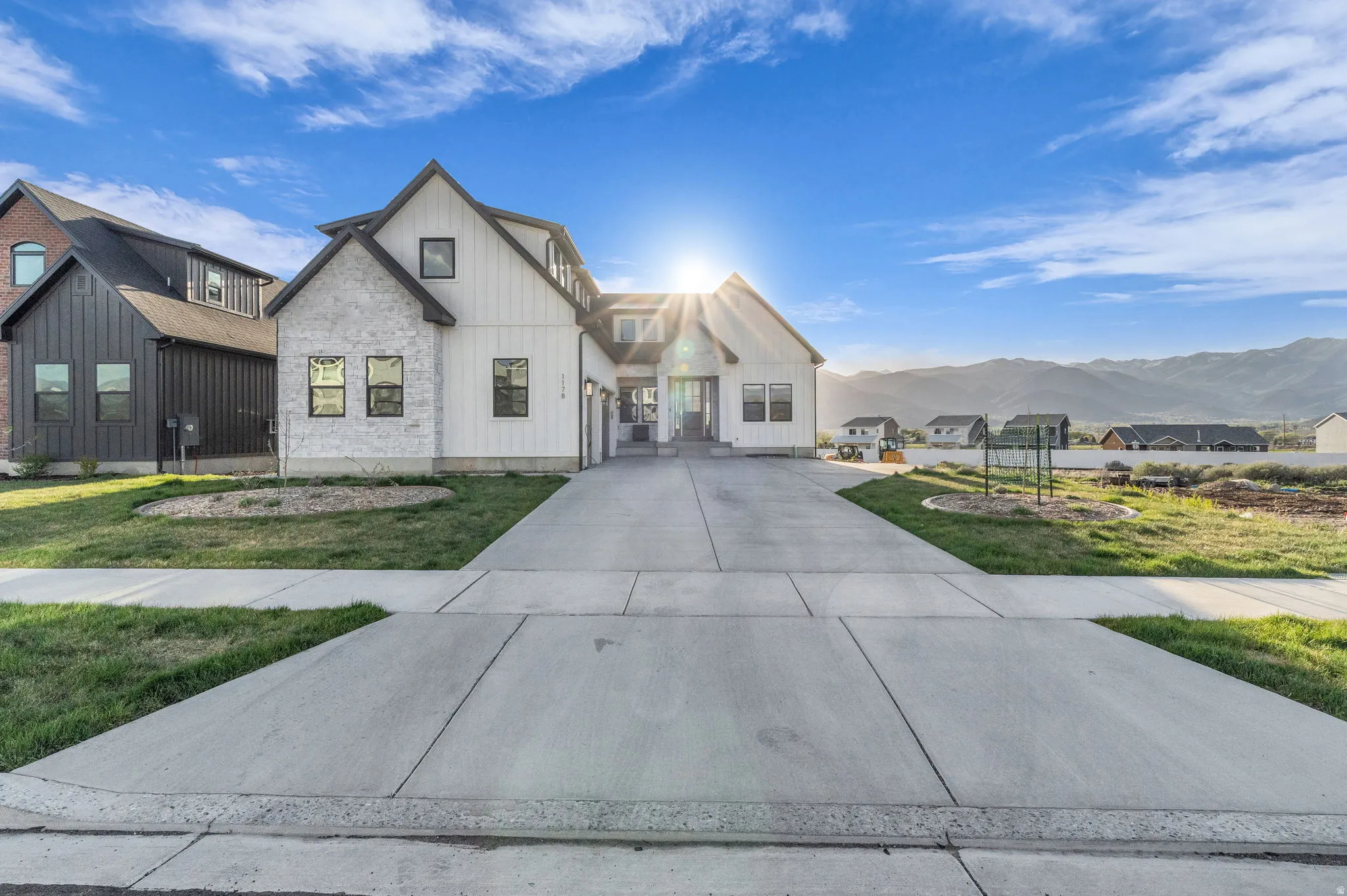 Modern farmhouse style home with board and batten siding, a mountain view, a front yard, and stone siding