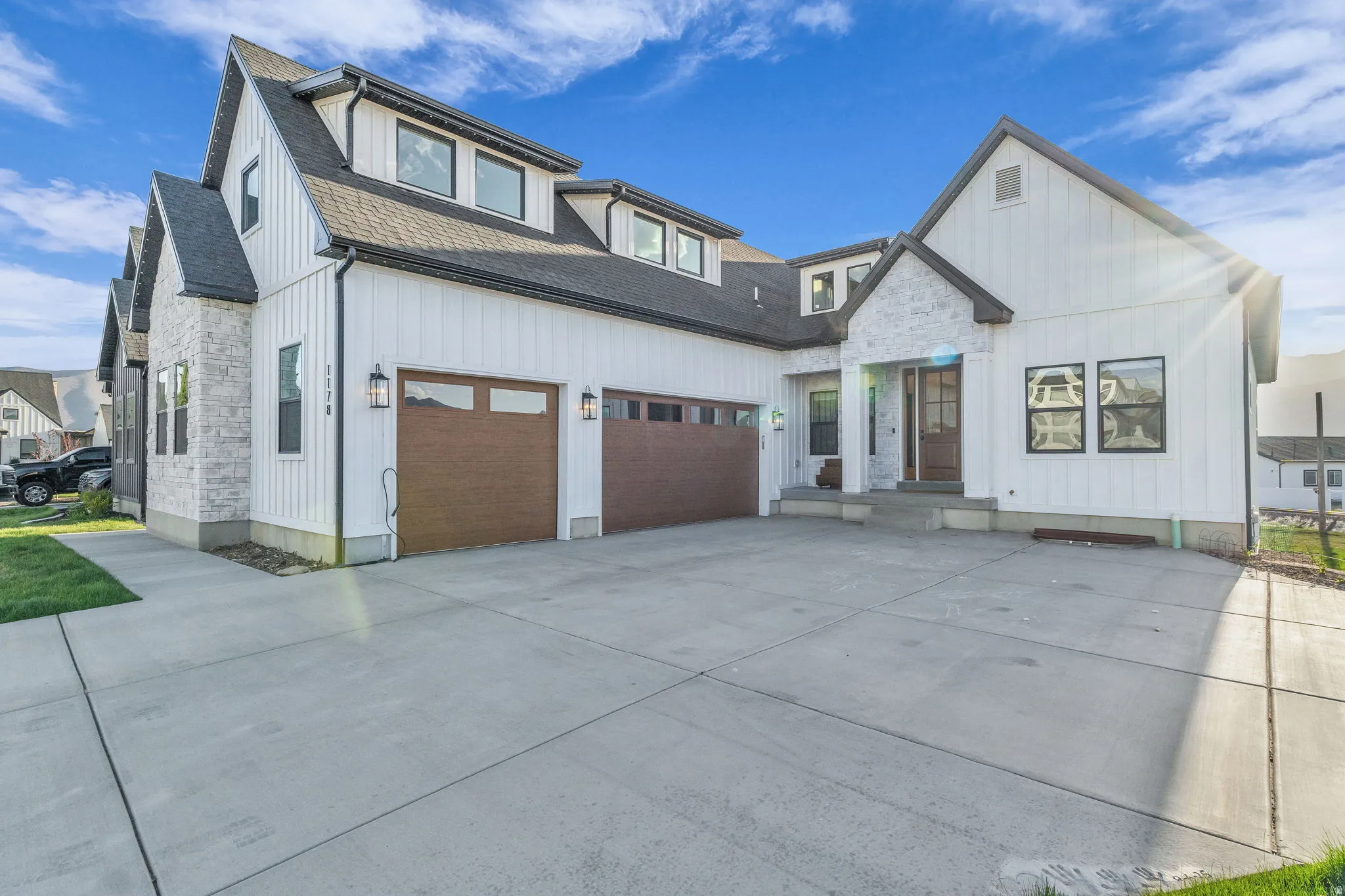 Modern farmhouse style home with stone siding, a shingled roof, concrete driveway, and board and batten siding