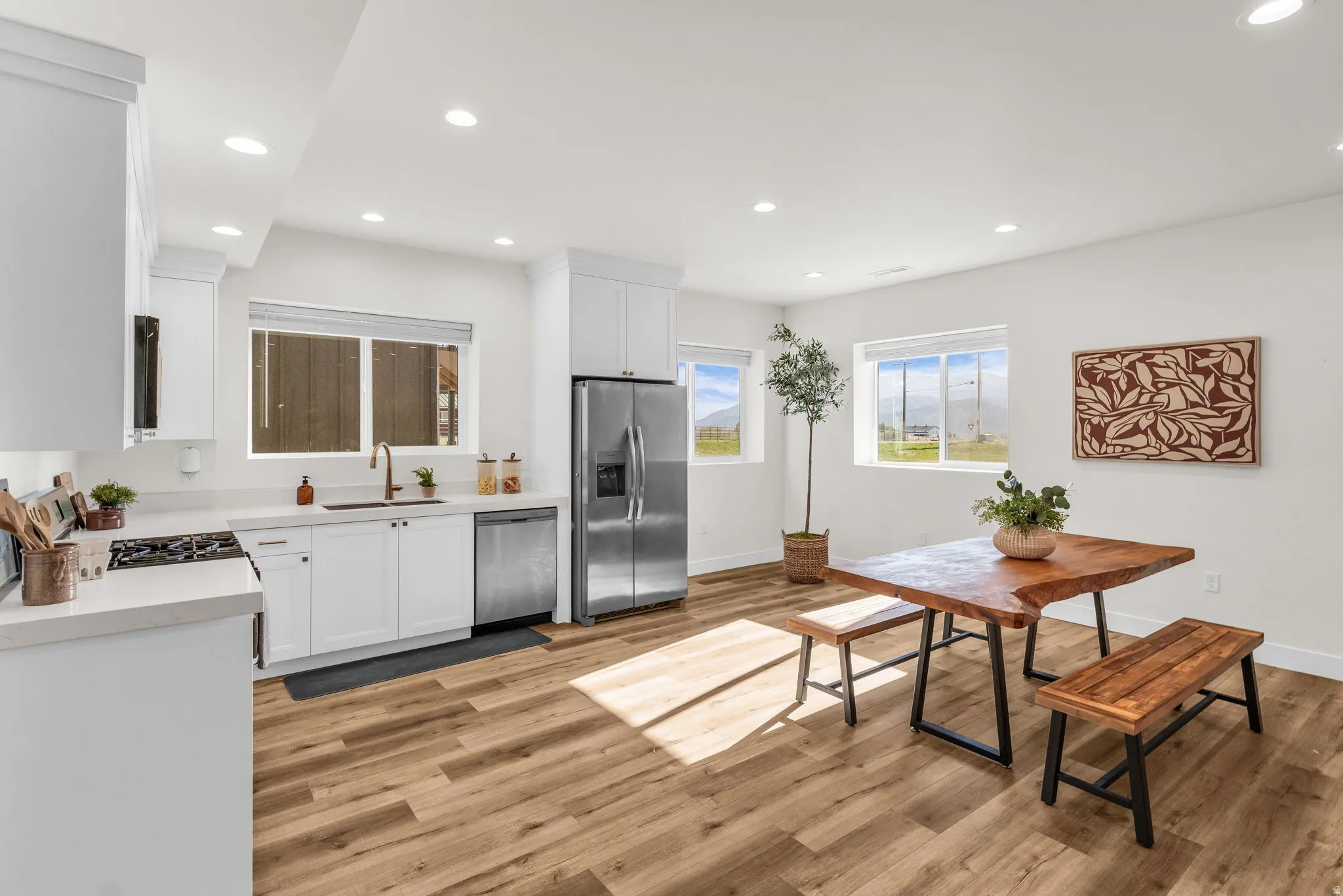 Kitchen with white cabinets, stainless steel appliances, light wood-style floors, and recessed lighting