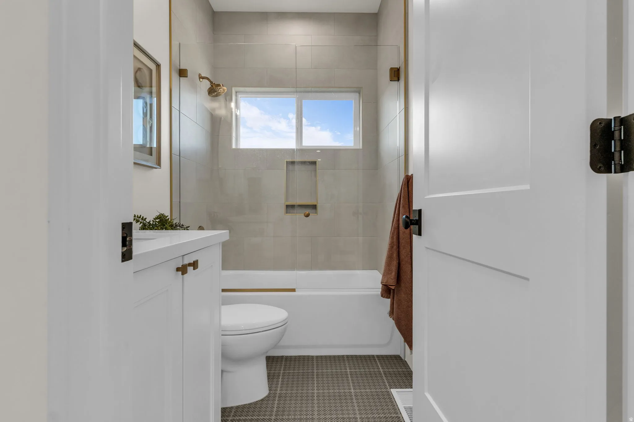 Bathroom with vanity, bath / shower combo with glass door, and light tile patterned flooring