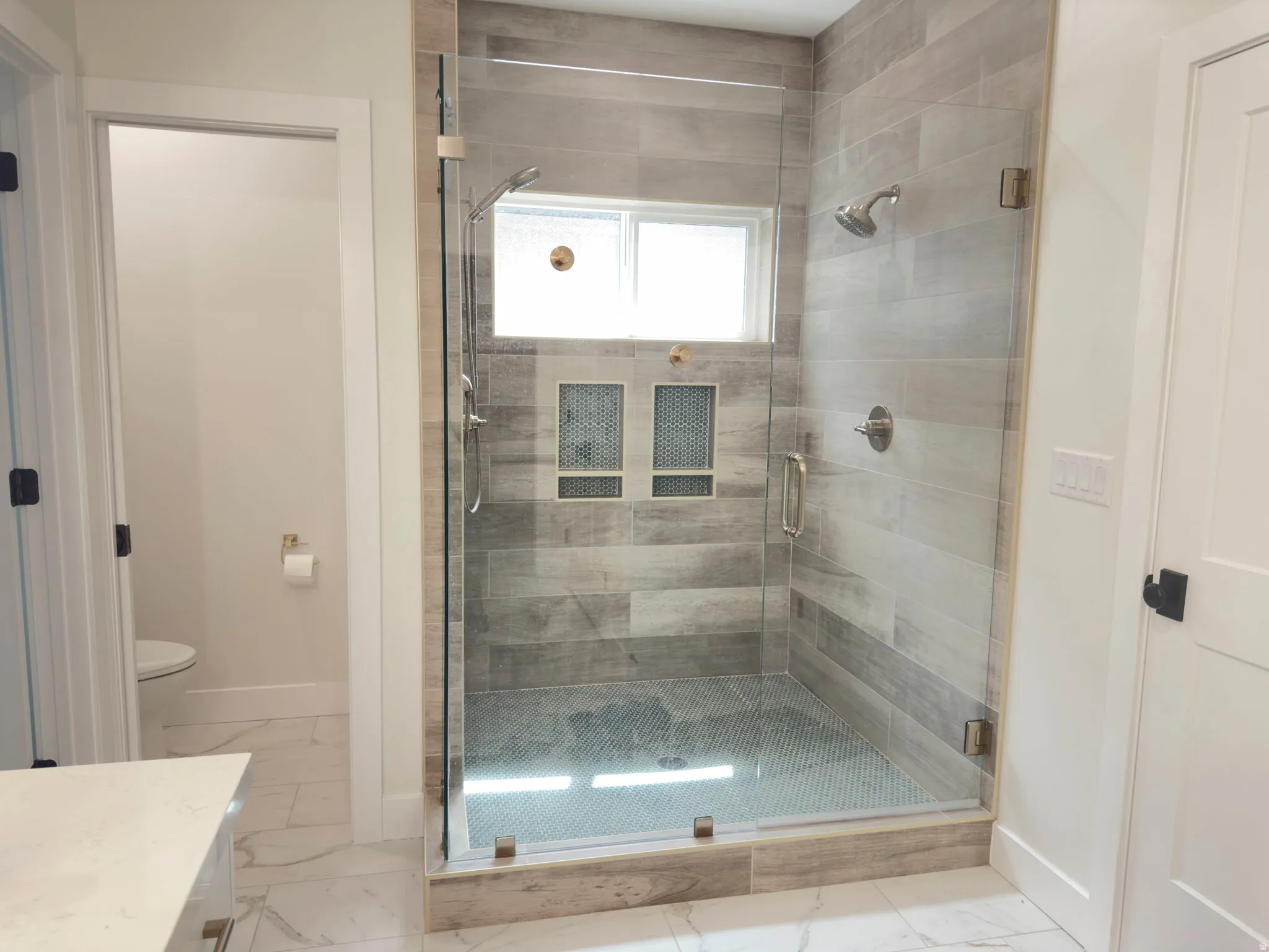 Bathroom with a shower stall, light marble finish floors, and vanity