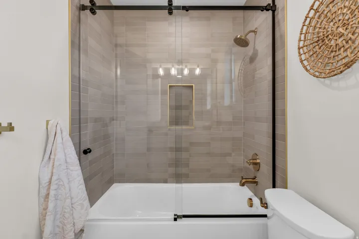 Full bathroom featuring toilet and shower / bath combination with glass door