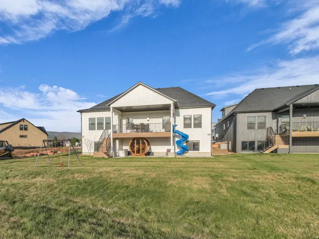 Back of house with a balcony, a playground, and a patio