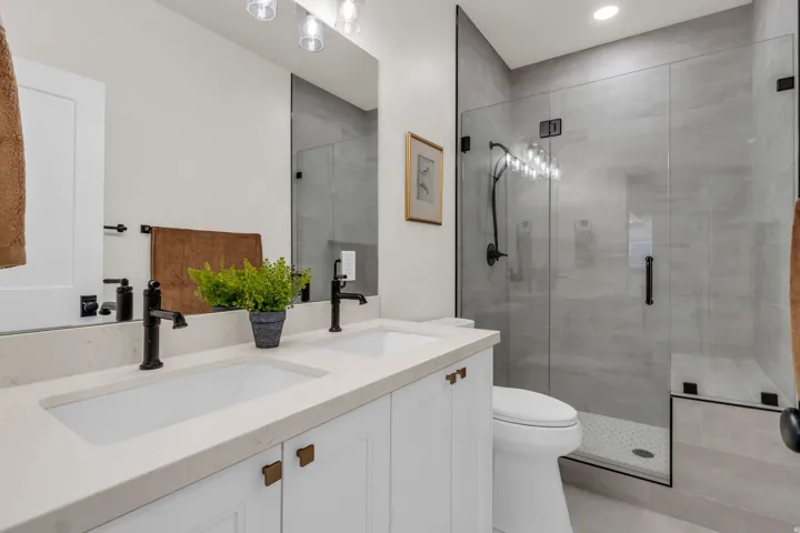 Full bathroom featuring double vanity and a shower stall