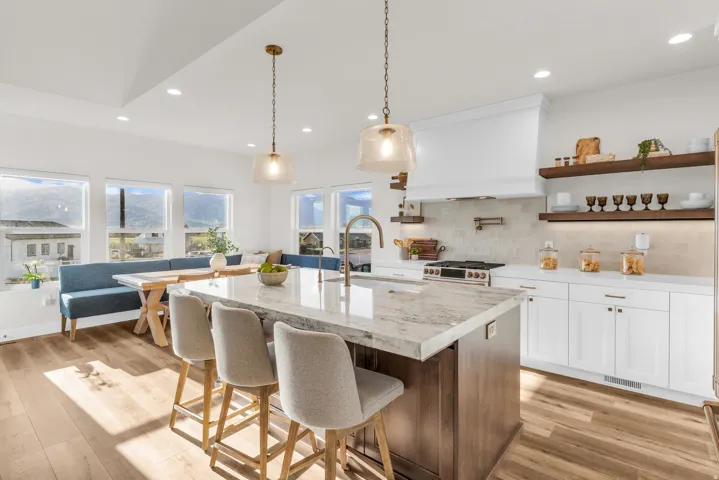 Kitchen featuring a kitchen island with sink, a kitchen breakfast bar, two tone color scheme, pendant lighting, and light wood-type flooring
