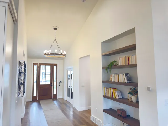 Foyer with dark wood-type flooring, a chandelier, and vaulted ceiling