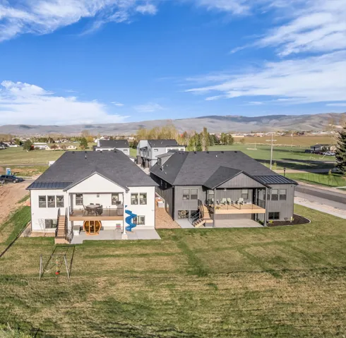 Rear view of house with a patio, a mountain view, and a lawn