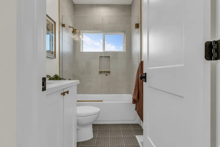 Bathroom with vanity, bath / shower combo with glass door, and light tile patterned flooring