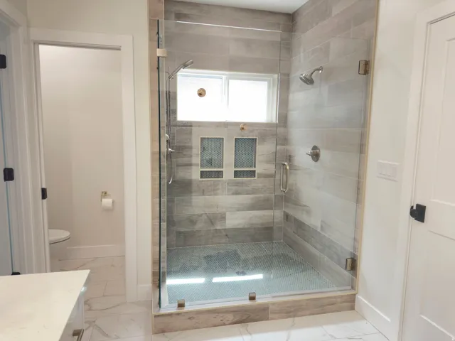 Bathroom with a shower stall, light marble finish floors, and vanity