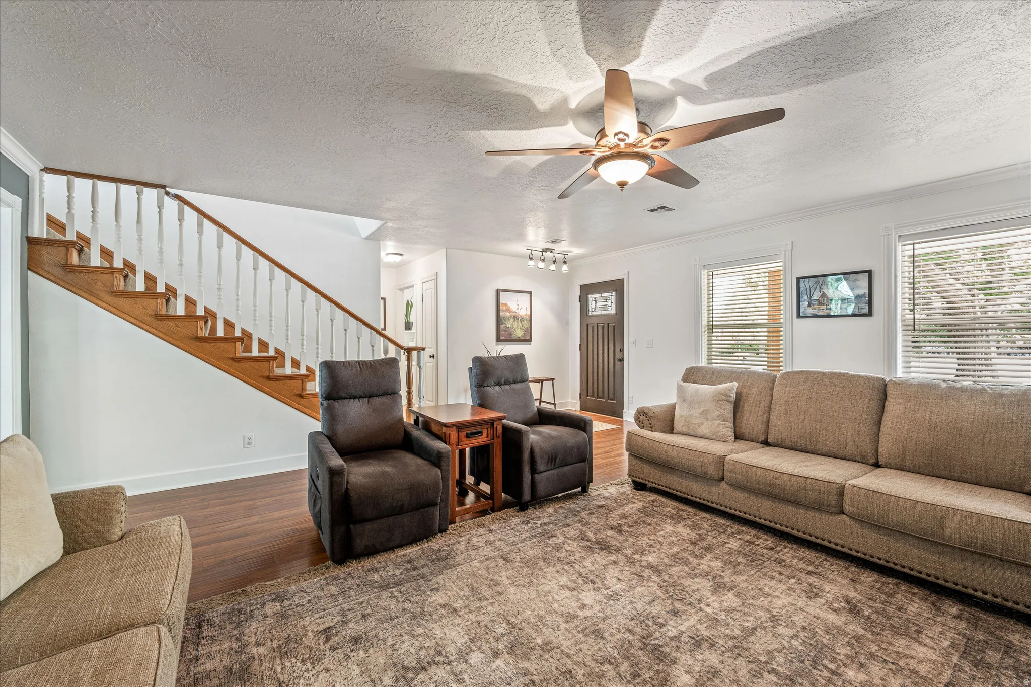 Living area featuring wood finished floors, a textured ceiling, a ceiling fan, and ornamental molding