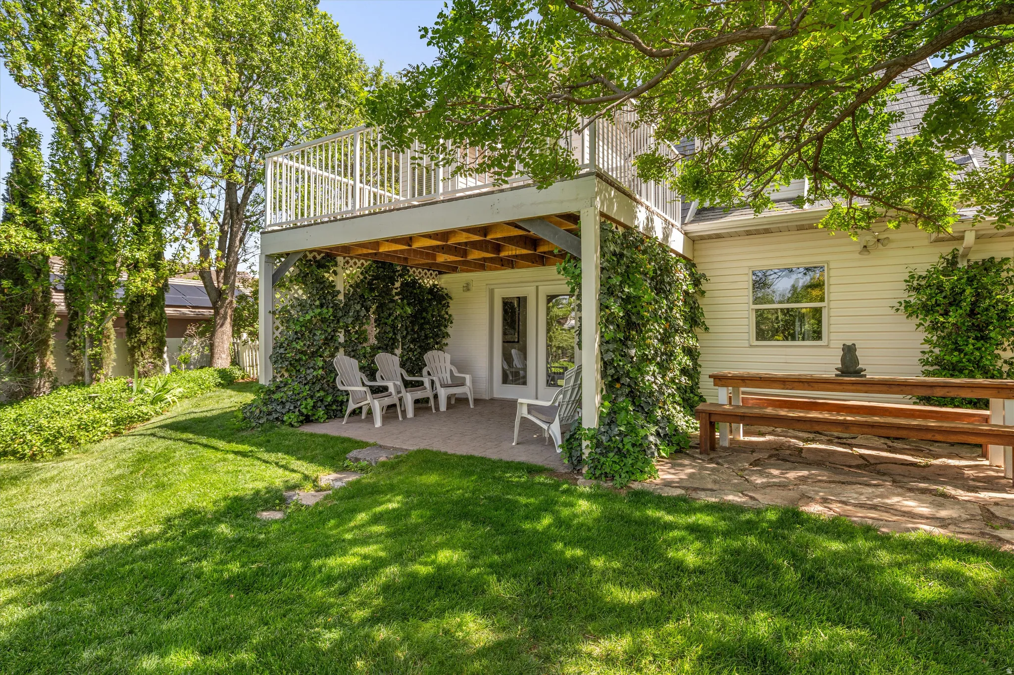 Rear view of house featuring a patio, a lawn, a wooden deck, and french doors