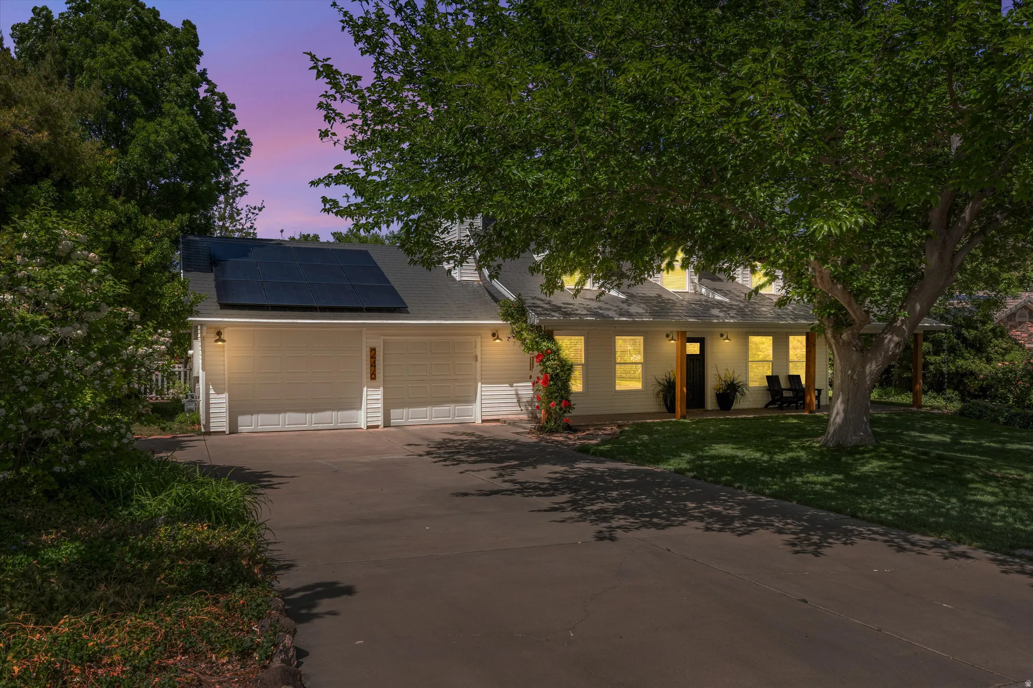View of front of property with solar panels, driveway, a front lawn, an attached garage, and roof with shingles
