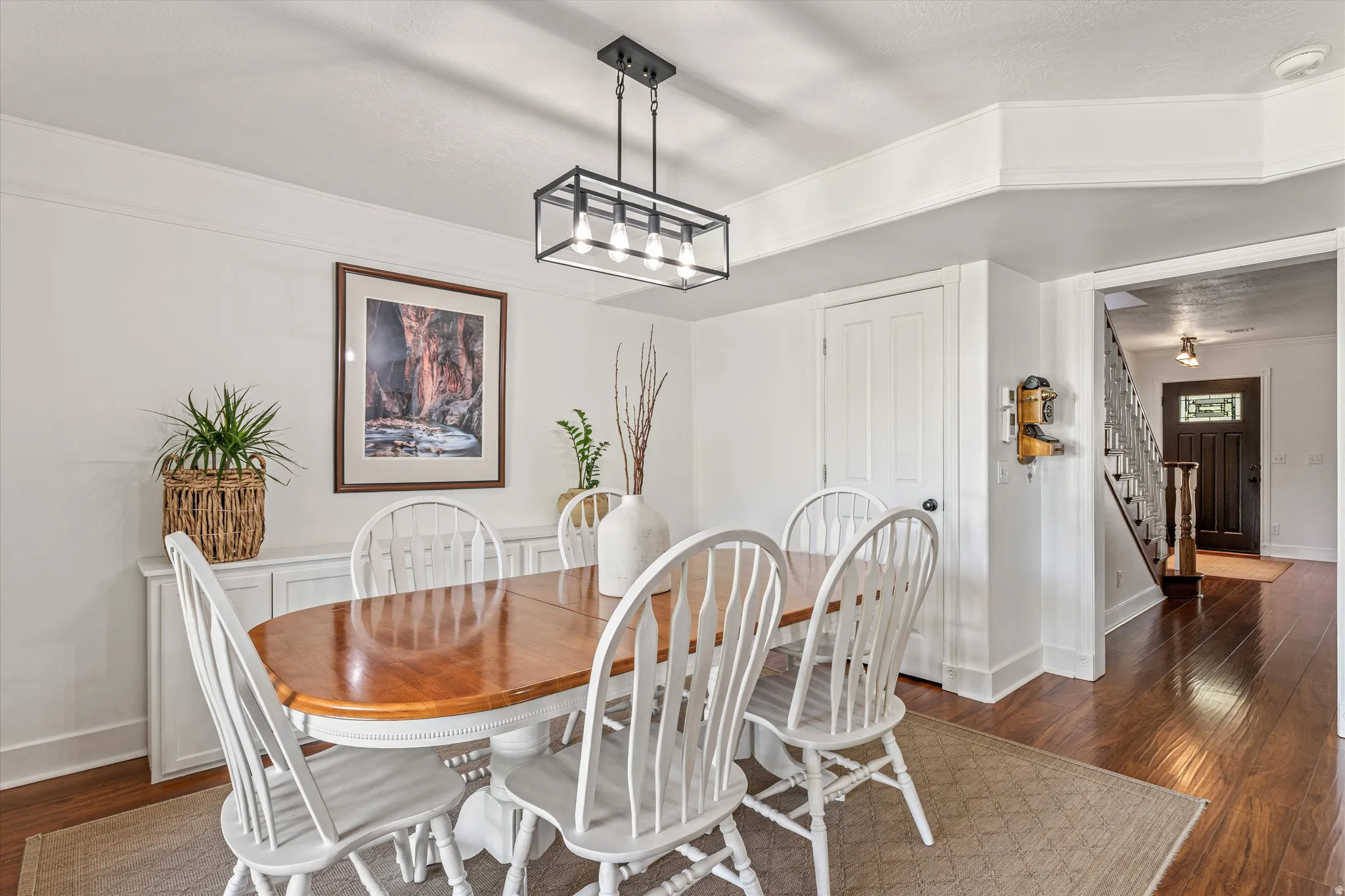 Dining area featuring dark wood-style floors and suspended lighting