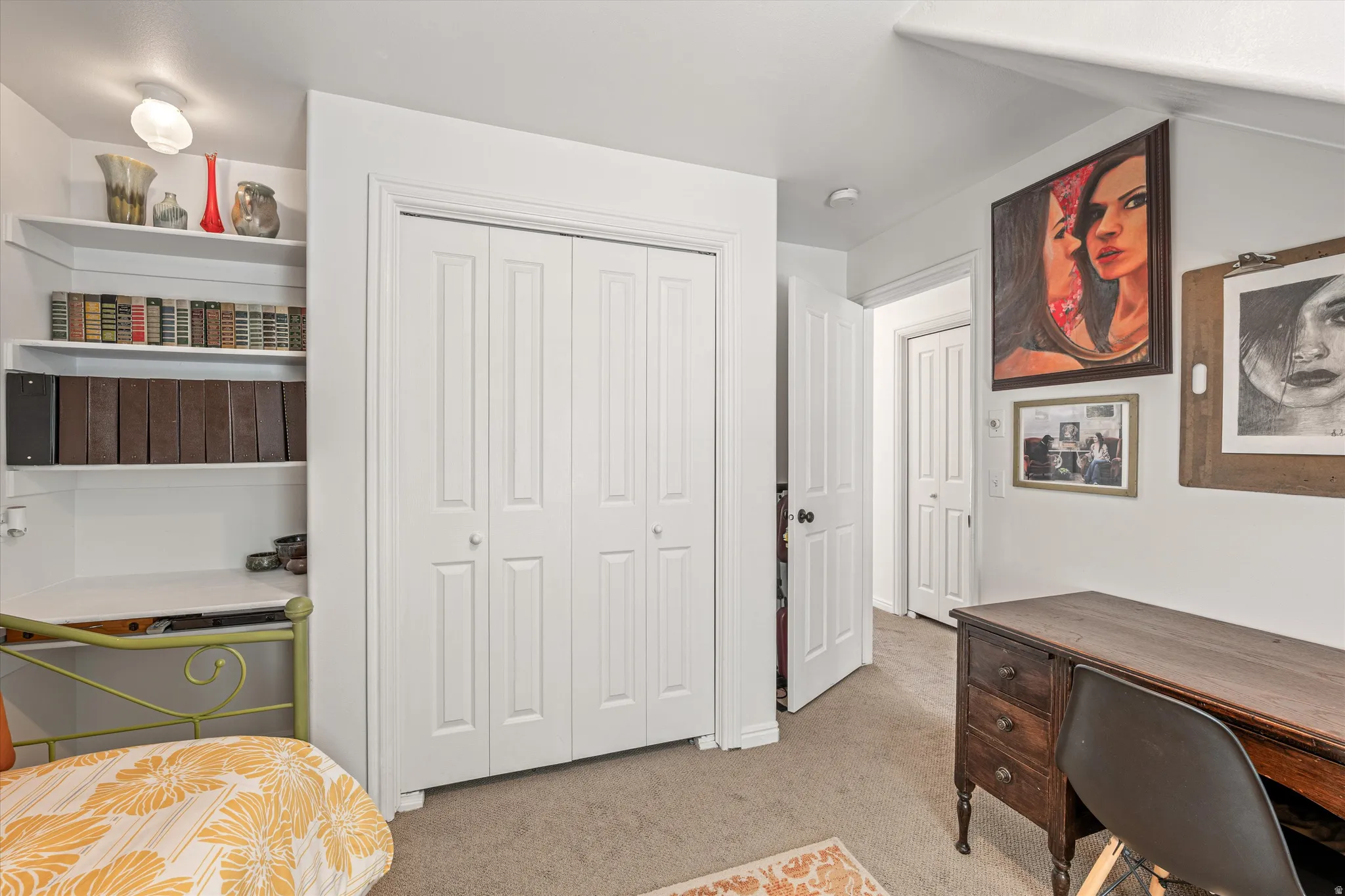 Bedroom with light colored carpet, a desk, and a closet