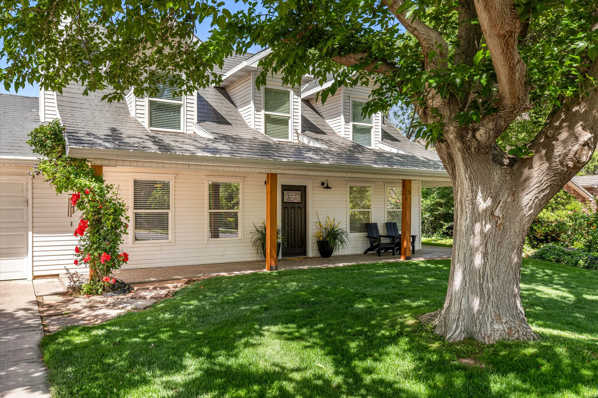 Cape cod-style house with a front lawn, covered porch, and roof with shingles