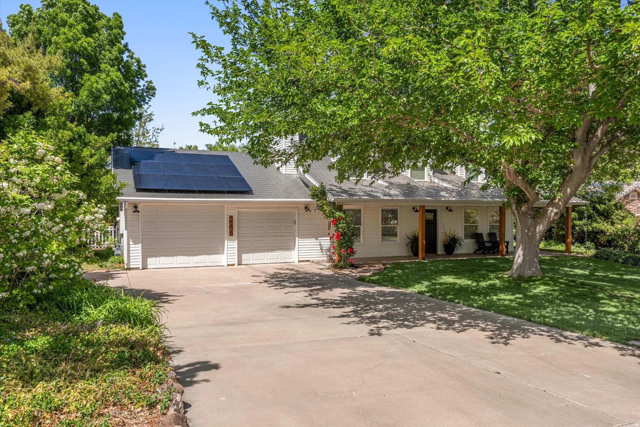 View of front of home featuring roof mounted solar panels, concrete driveway, a garage, and a shingled roof