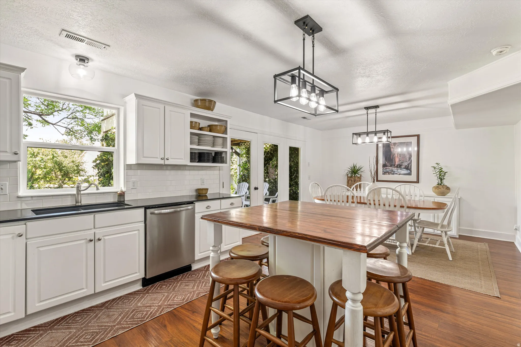 Kitchen with french doors, white cabinetry, backsplash, dishwasher, and dark wood-type flooring