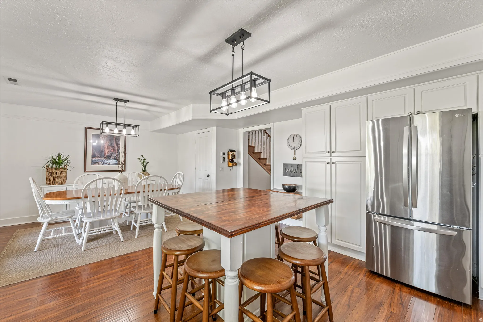 Kitchen with freestanding refrigerator, wooden counters, a textured ceiling, white cabinets, and dark wood-style floors