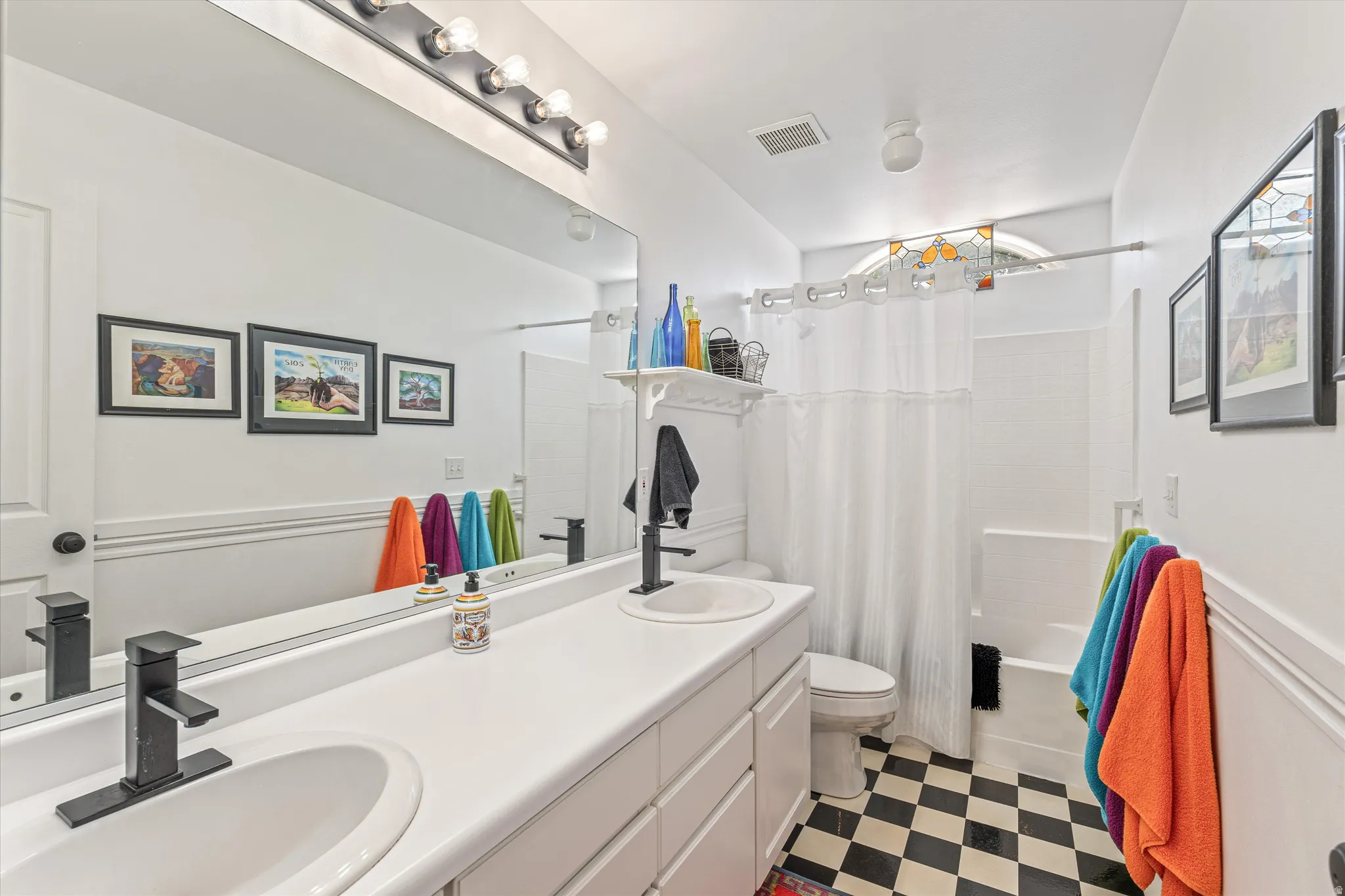 Full bath with light floors, double vanity, and shower / tub combo