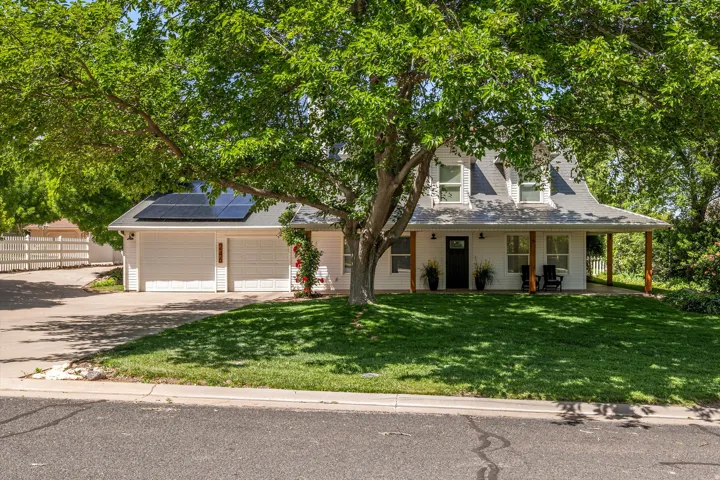 View of front of property with solar panels, driveway, a garage, and a porch