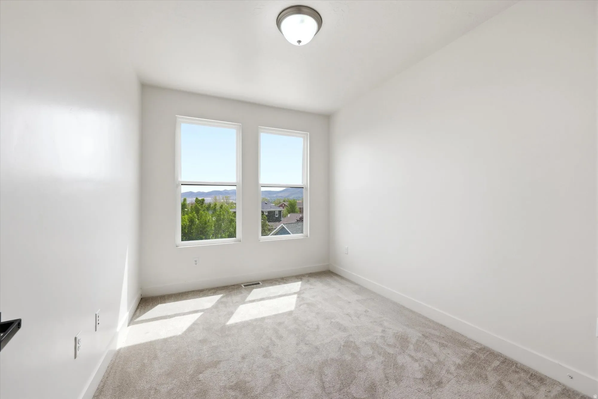 Spare room featuring light carpet and baseboards