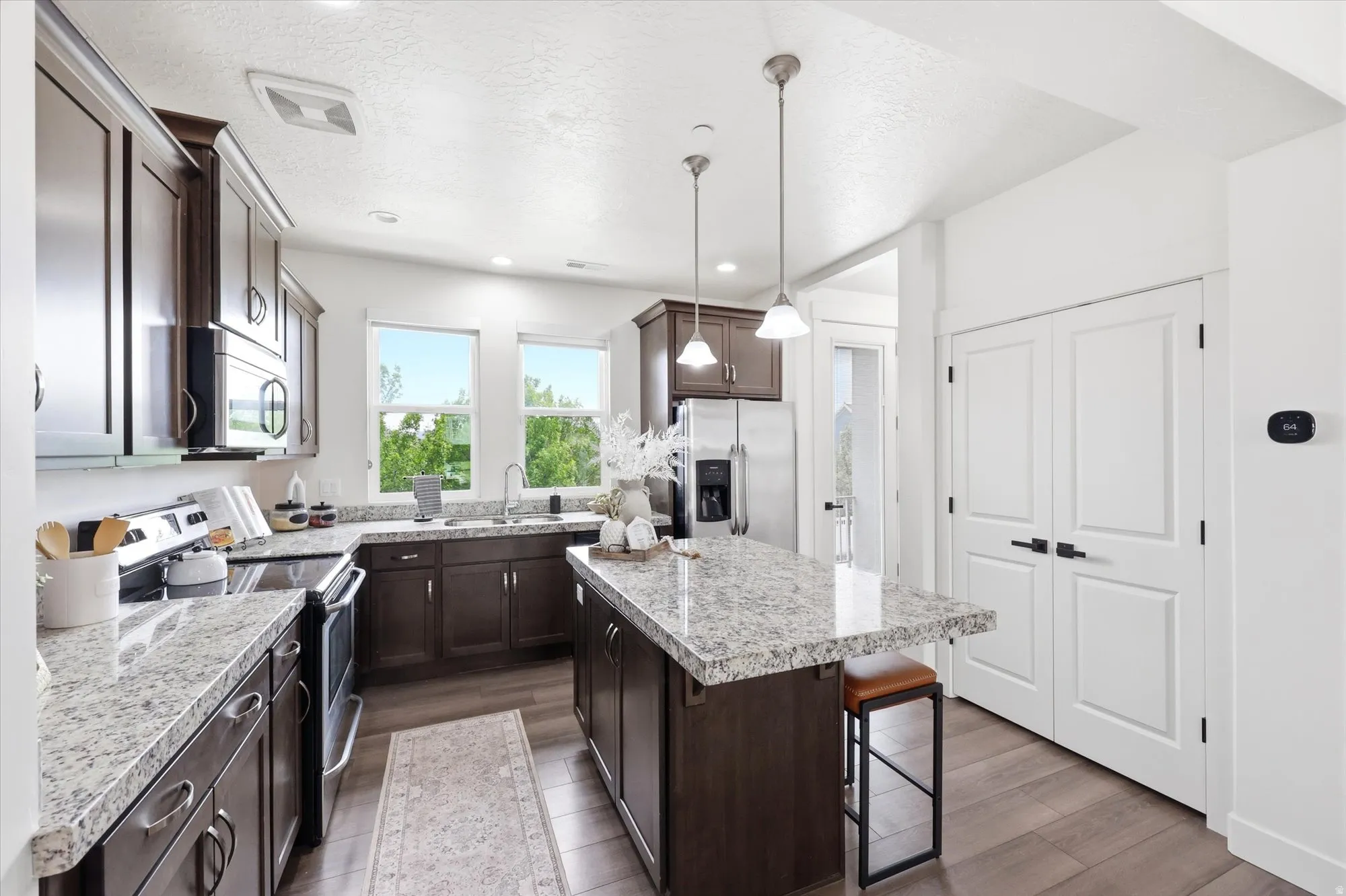 Kitchen featuring stainless steel appliances, dark wood finish cabinets, a kitchen island, dark wood-style flooring, and a kitchen breakfast bar