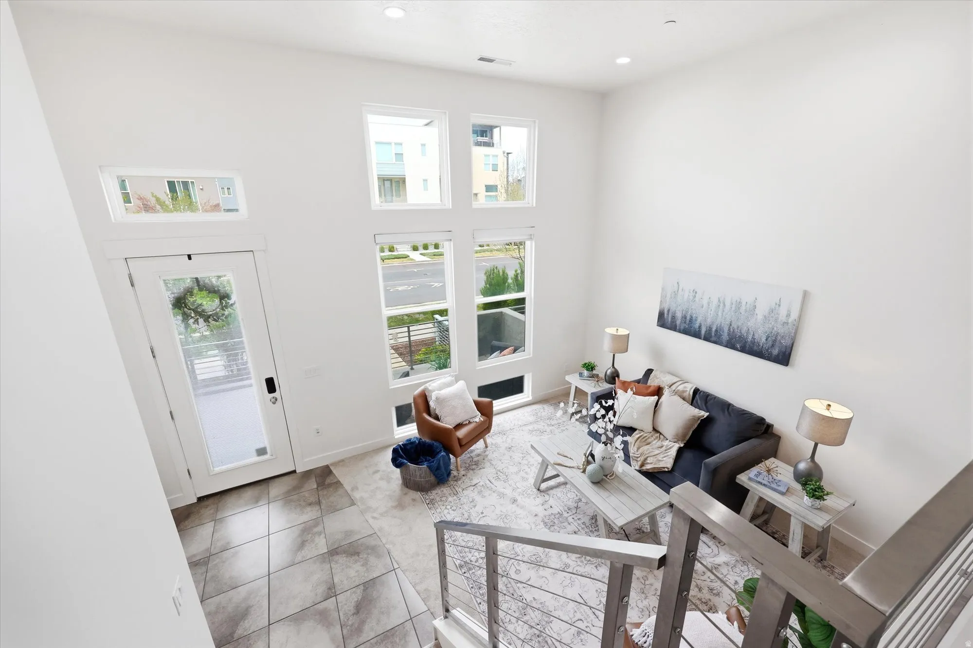 Living area with a high ceiling, plenty of natural light, light tile patterned flooring, and recessed lighting