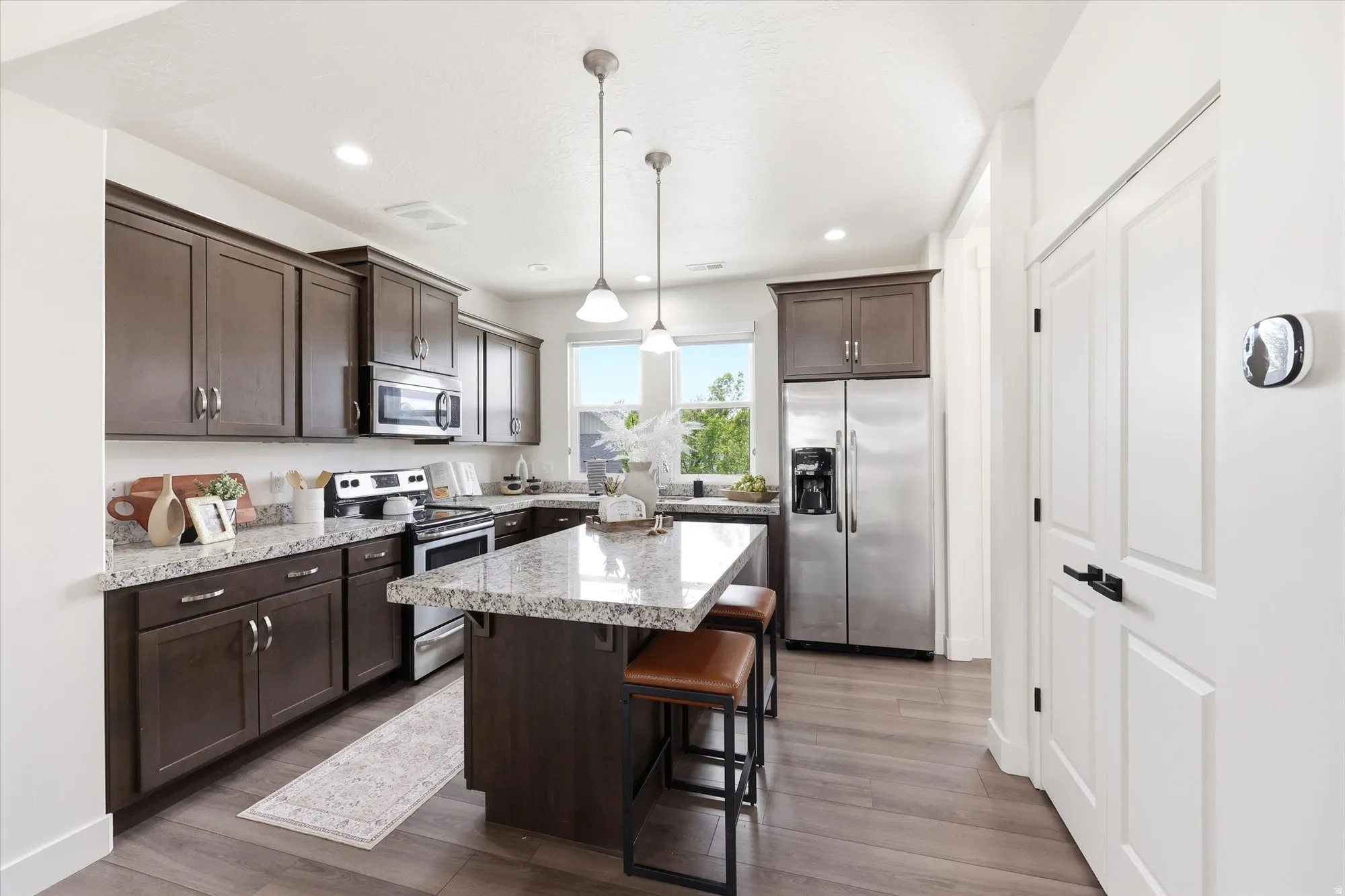 Kitchen with dark wood finish cabinets, stainless steel appliances, a kitchen breakfast bar, a kitchen island, and dark wood finished floors