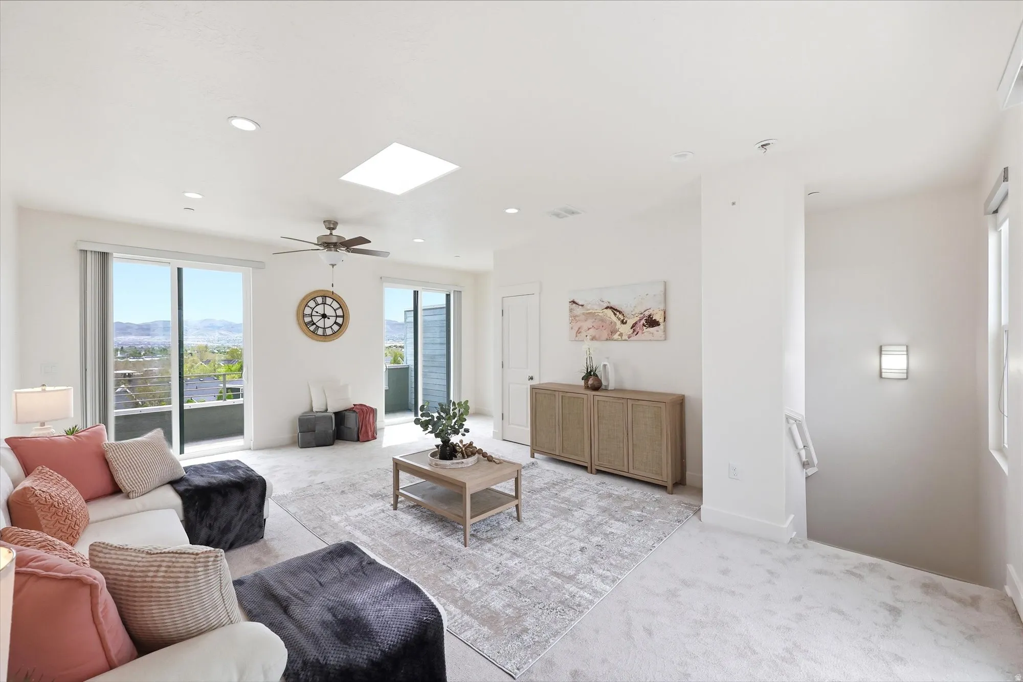 Living room with light colored carpet, a skylight, a mountain view, recessed lighting, and a ceiling fan
