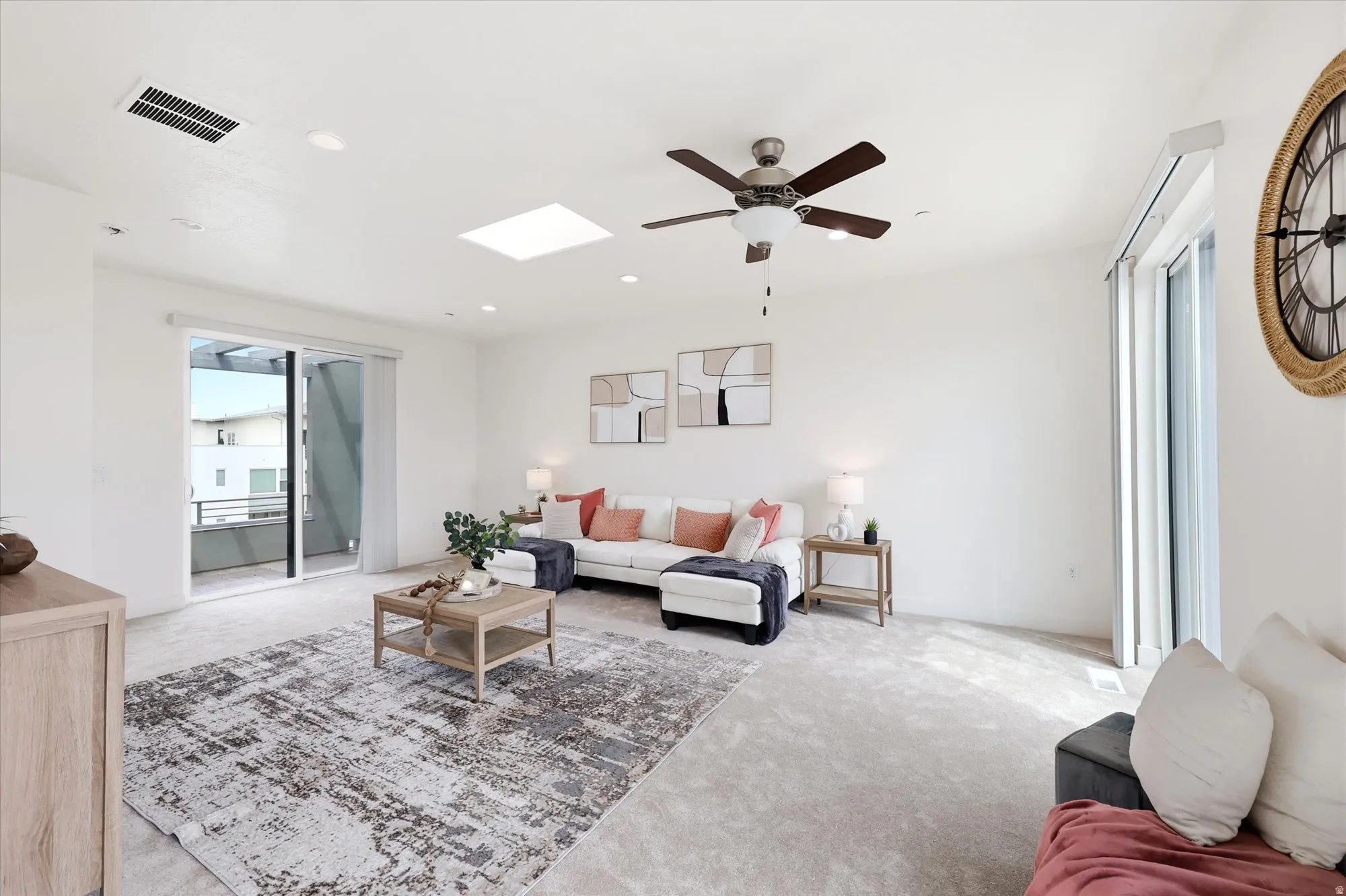 Carpeted living area with ceiling fan, a skylight, and recessed lighting