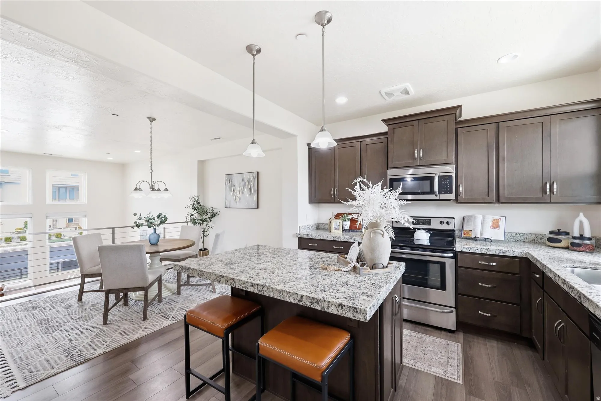 Kitchen with stainless steel appliances, dark wood finish cabinets, dark wood finished floors, a center island, and a kitchen bar