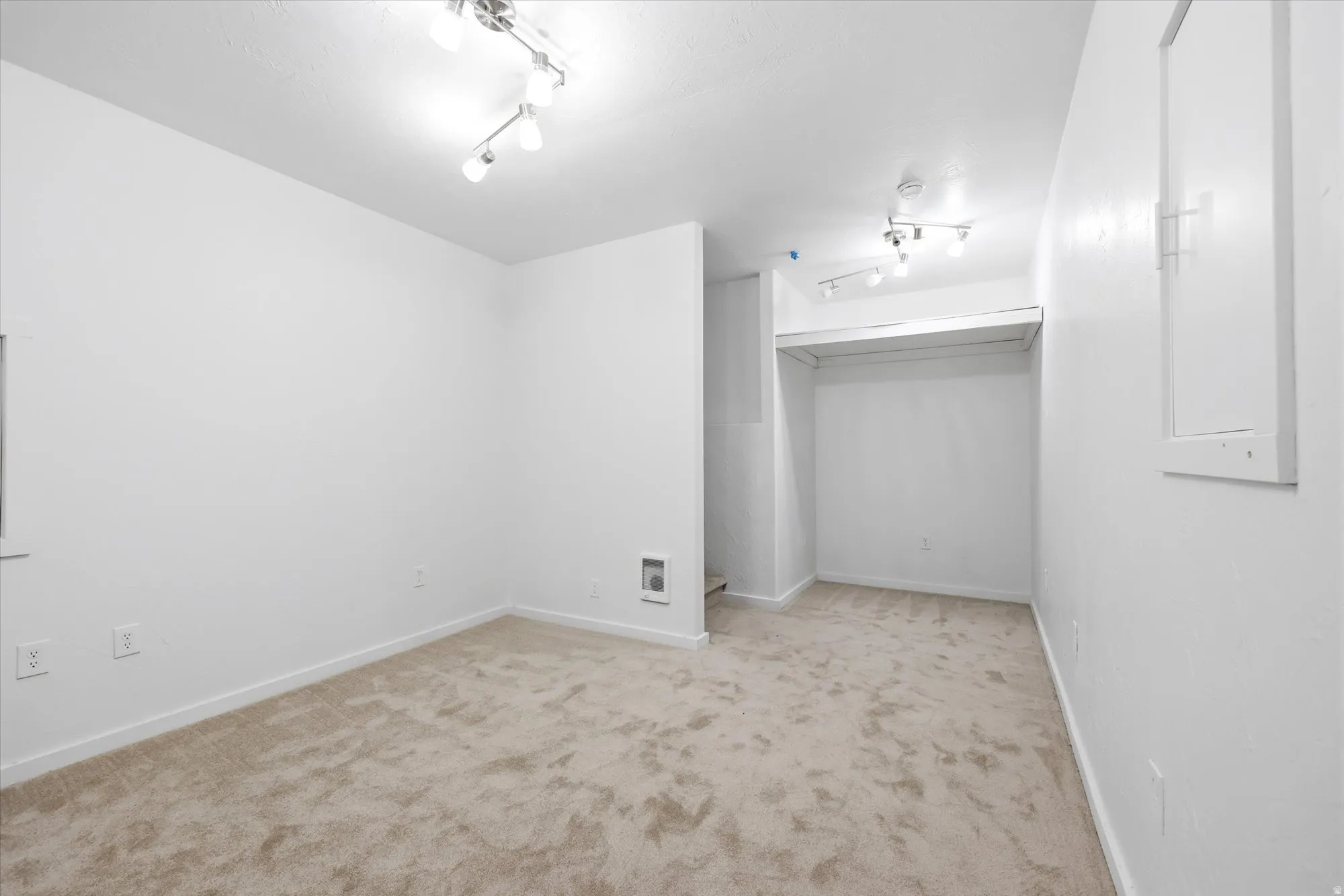 Basement bonus room featuring light colored carpet and baseboards