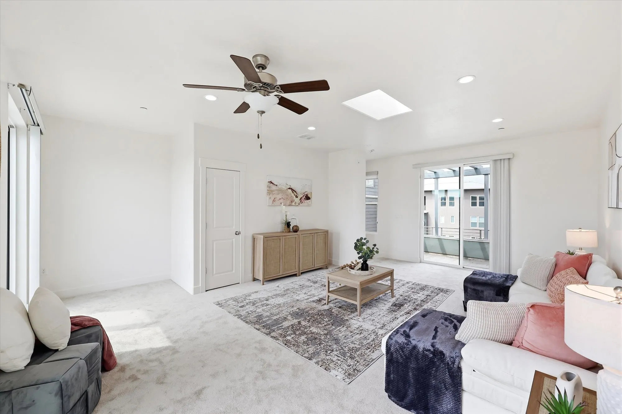 Living room with carpet floors, a ceiling fan, a skylight, and recessed lighting