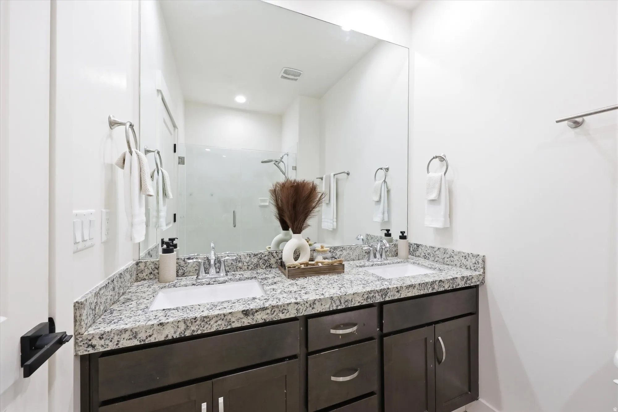 Full bathroom featuring double vanity and a stall shower