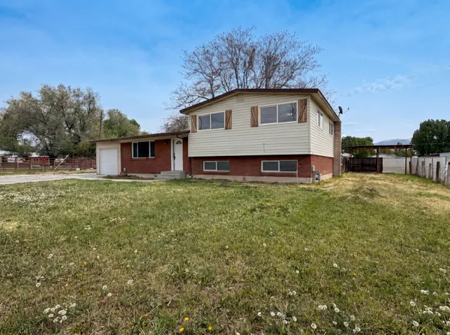 Split level home with an attached garage, brick siding, and concrete driveway