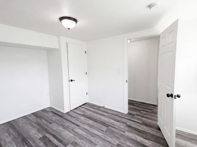 Unfurnished bedroom featuring dark wood-type flooring and baseboards