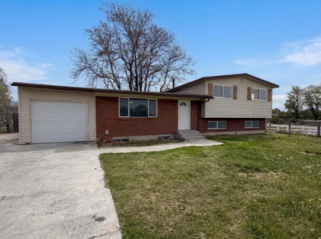 Tri-level home featuring an attached garage, brick siding, and driveway