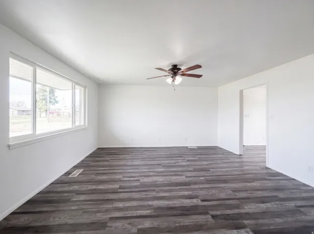 Unfurnished room featuring a ceiling fan and dark wood-style flooring