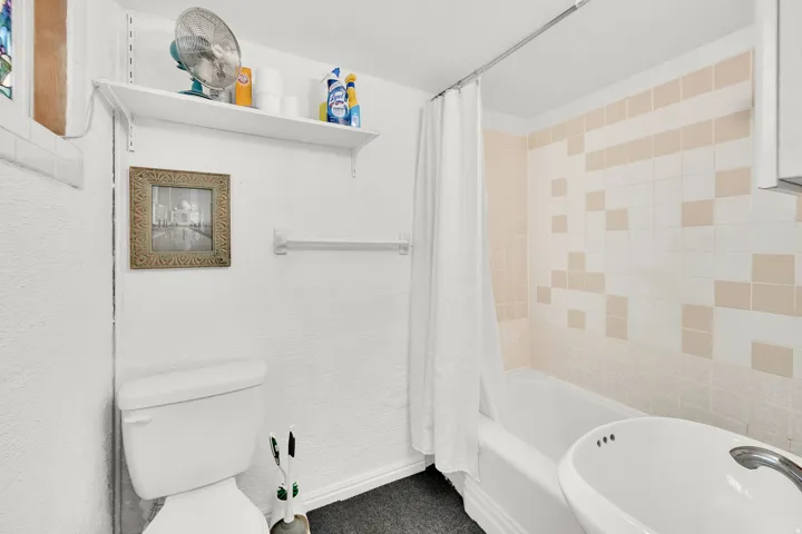 Full bathroom featuring toilet and shower / bathtub combination with curtain