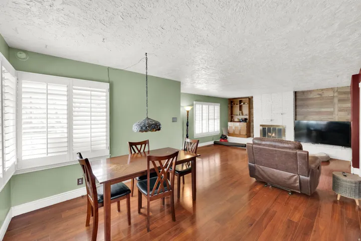 Dining room featuring dark wood-style flooring, a brick fireplace, and a textured ceiling