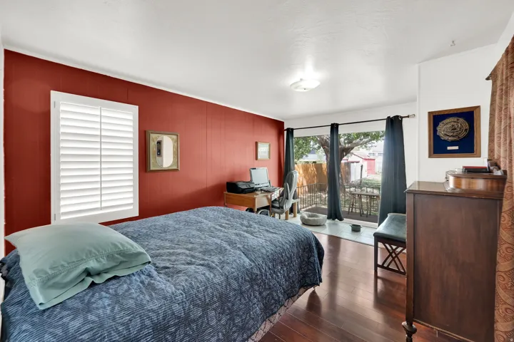 Bedroom with access to exterior, dark wood-type flooring, and wood walls