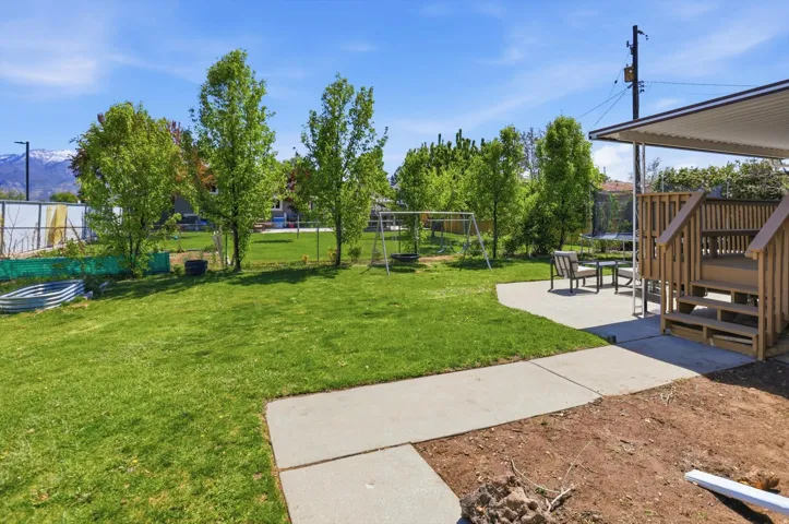 Fenced backyard with a trampoline, a playground, and a patio