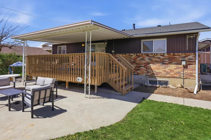 Rear view of property featuring outdoor lounge area, brick siding, a deck, and roof with shingles